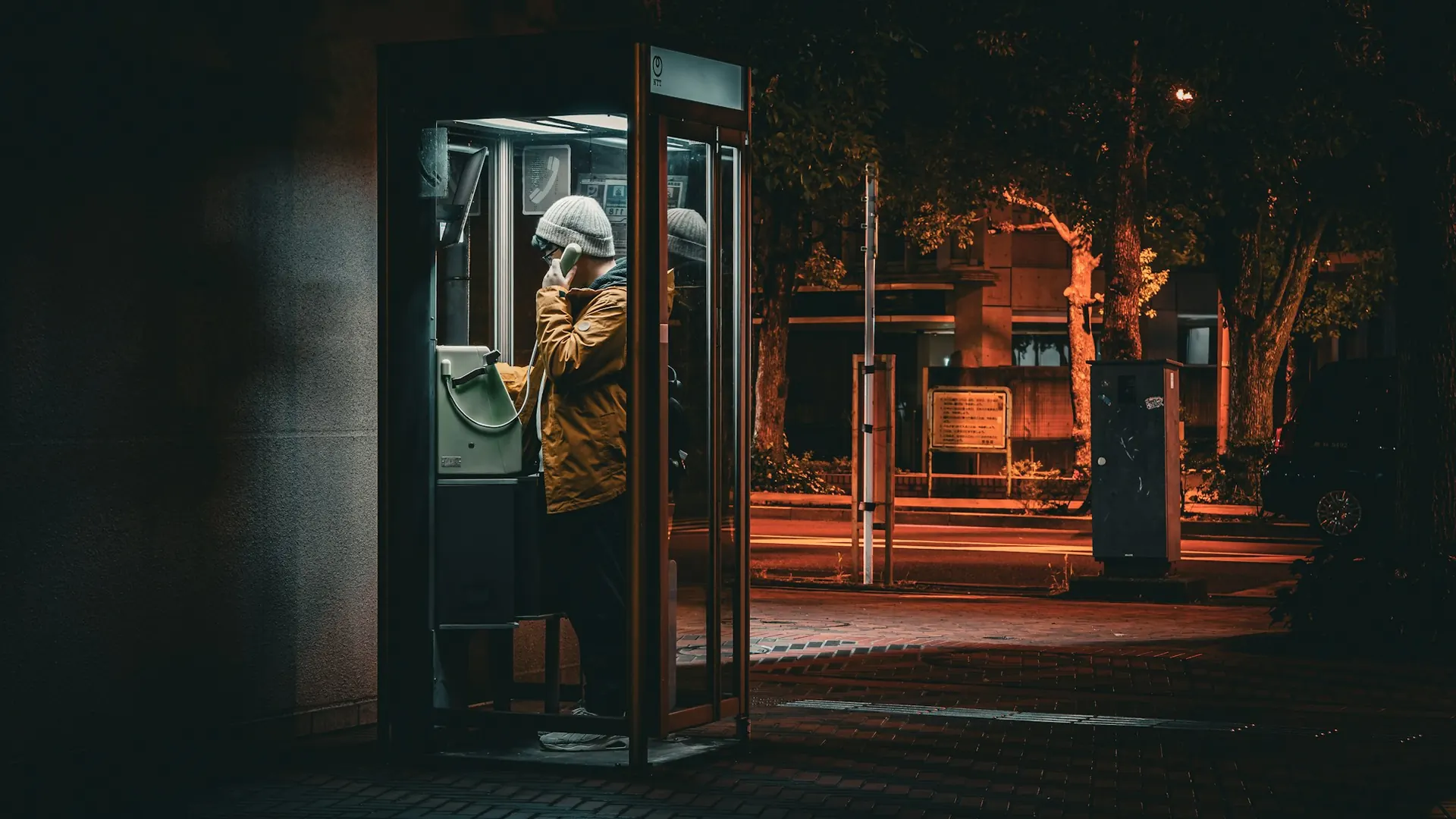 Person using a payphone at night